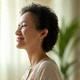 Calm woman in her mid-50s with a gentle smile, perhaps during a meditation break.